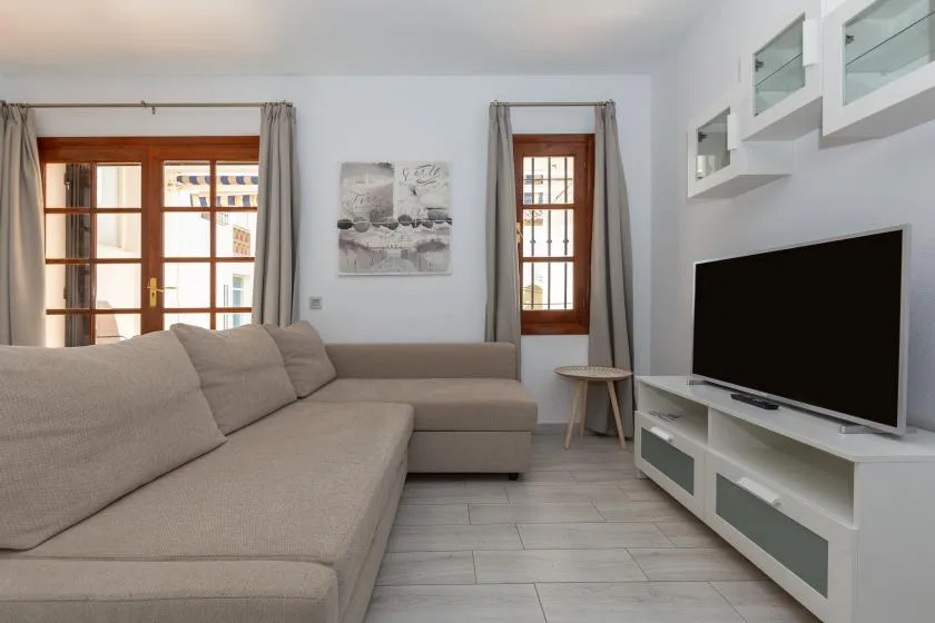 A bright living room with a large sectional sofa and television.