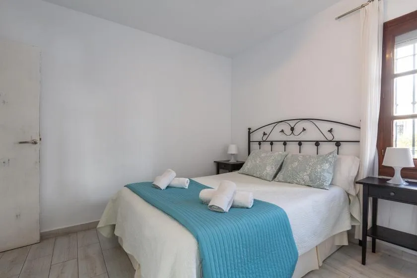 A bedroom with a double bed, teal runner, and bedside tables.