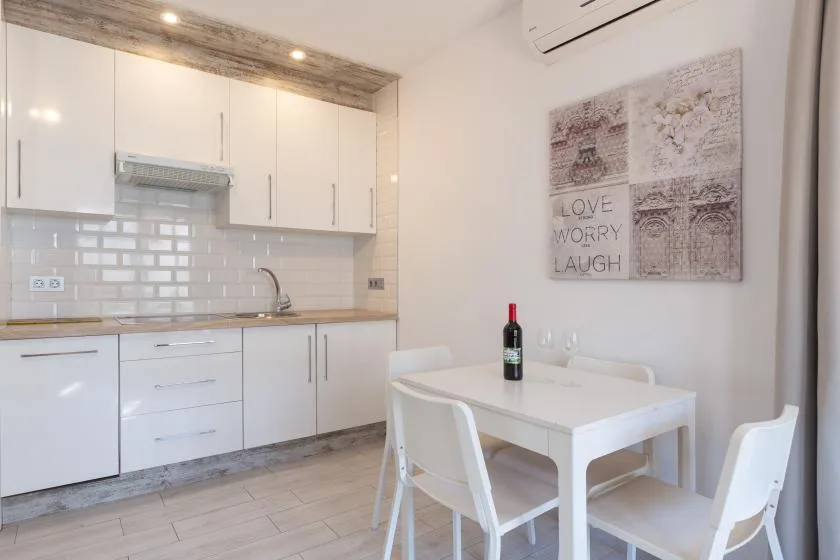 A bright kitchen and dining area with white cabinets and a small table.