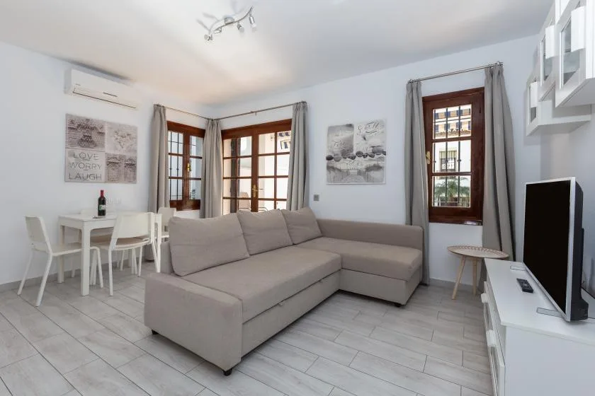A bright living room with a sectional seating area and a small dining table.