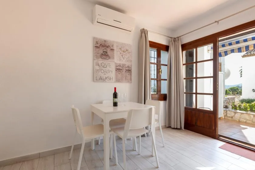 A bright dining area with a white table beside open wooden doors.