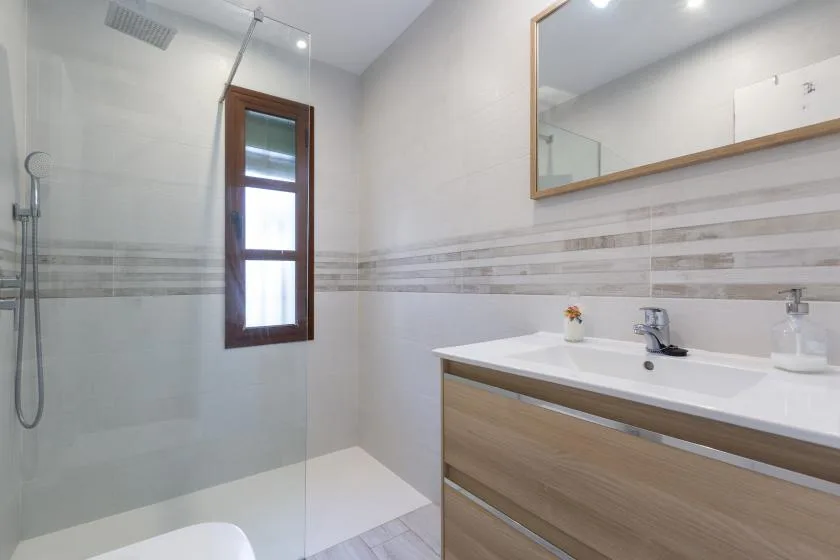 A bright bathroom with a glass shower area and a wood-toned vanity.