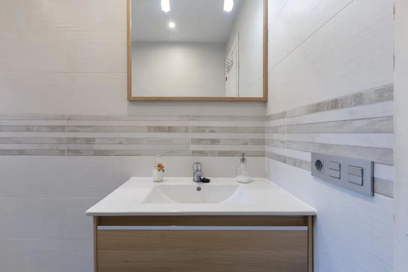 A bathroom vanity with a sink and mirror against tiled walls.