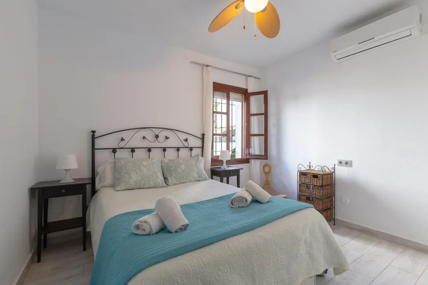 A bright bedroom with a bed beside an open window.