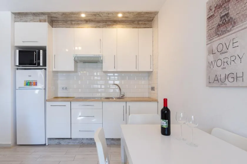 A bright kitchen with white cabinets and a dining table in the foreground.