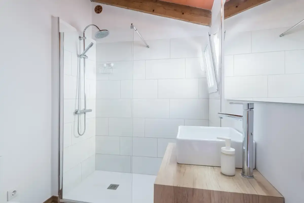 A bright bathroom with a walk-in shower and a wooden vanity.
