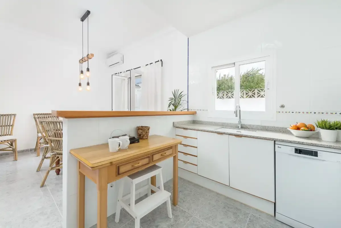A bright kitchen with a wooden island and a window above the sink.