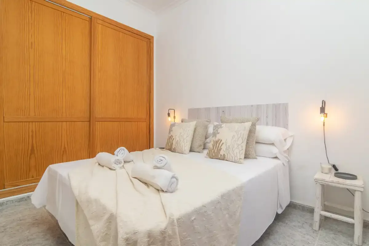 A bedroom with a neatly made bed and wooden wardrobe.