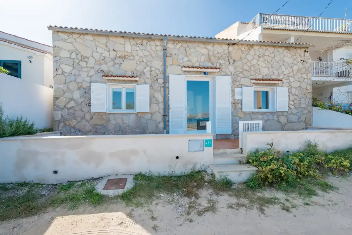 Stone-faced house exterior with blue shutters and a small front patio.