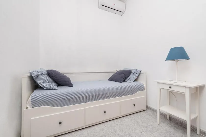 A bedroom with a single bed and a small bedside table.