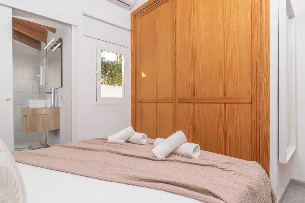A bedroom with a bed and a large wooden wardrobe.