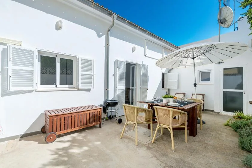 An outdoor dining area beside a white building, with a table and umbrella.