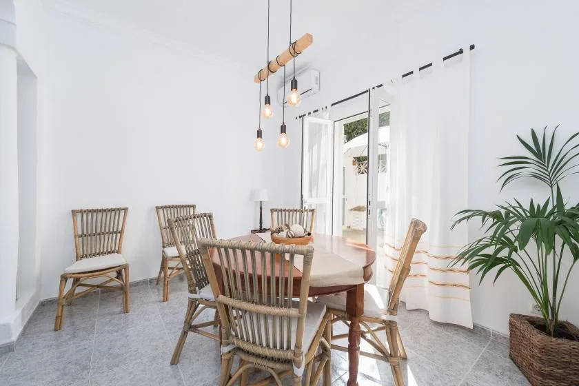 A bright dining area with a wooden table, seating, and curtains by the glass doors.