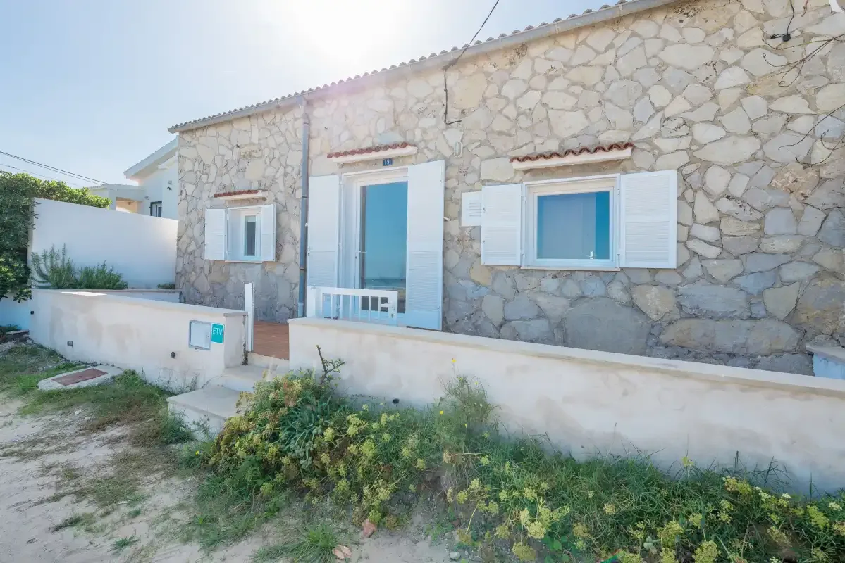 A stone-faced building with blue shutters and a small planted yard.