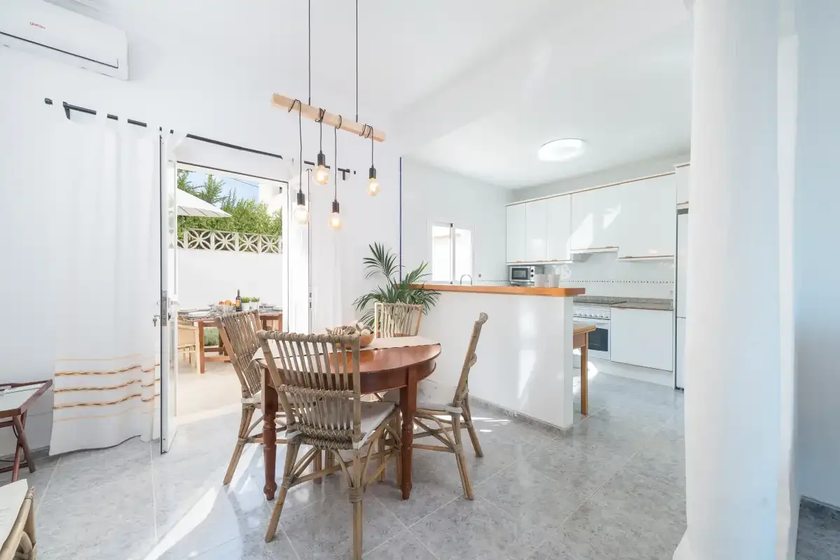 A bright dining area opens onto a patio beside a modern kitchen.