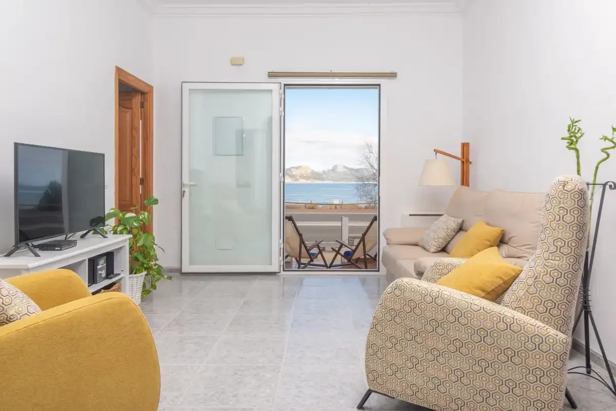 A bright living room with seating and glass doors opening onto a balcony.