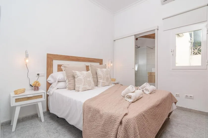 A bright bedroom with a neatly made bed and a small bedside table.