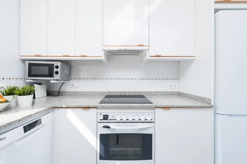 A bright kitchen with white cabinets, a countertop, and built-in appliances.