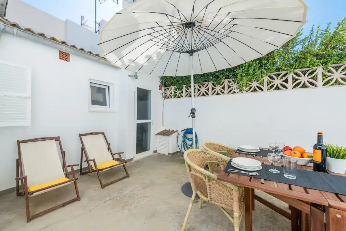 A patio dining area with a large umbrella, table, and outdoor seating.