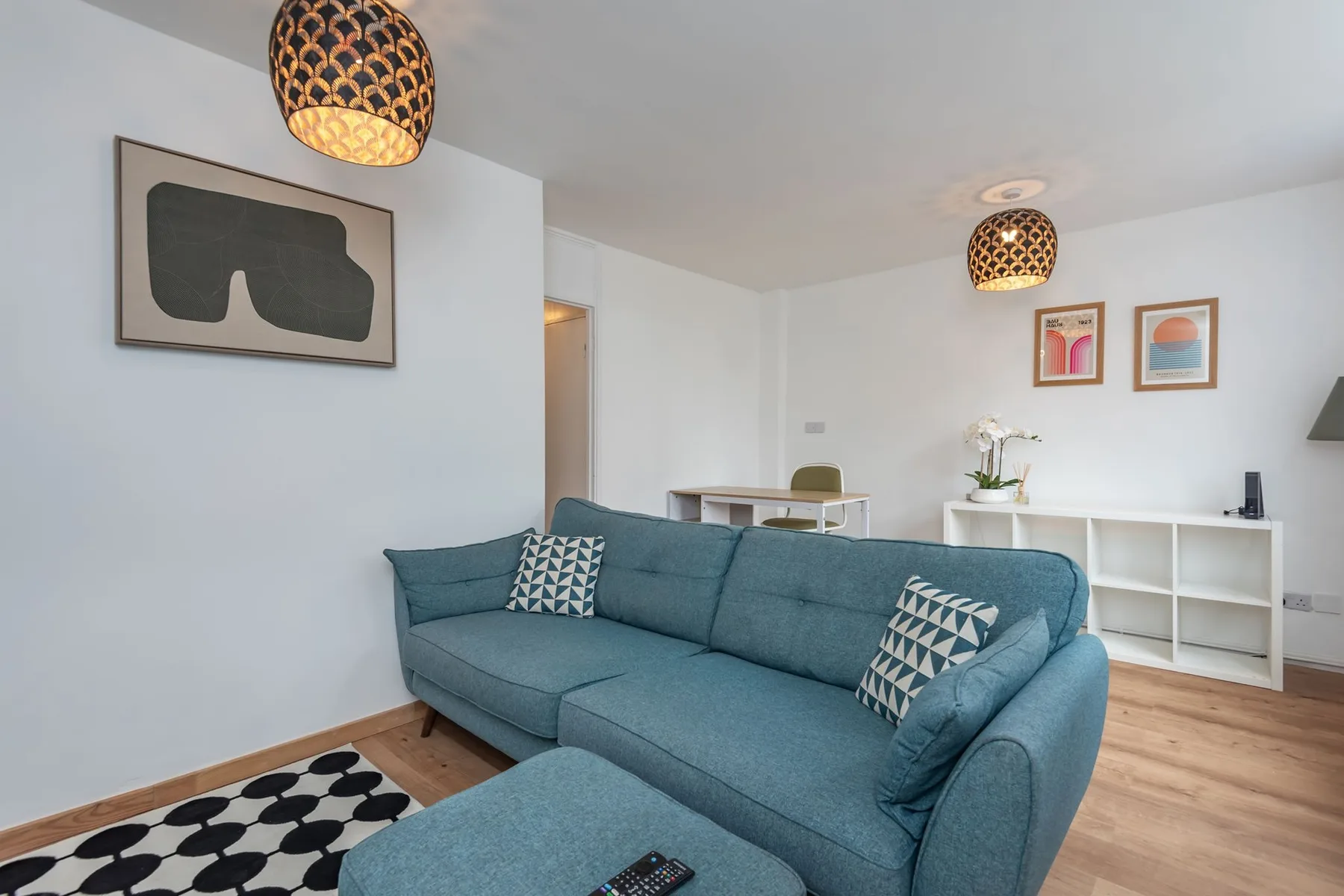 A bright living room with blue seating and framed artwork on the walls.