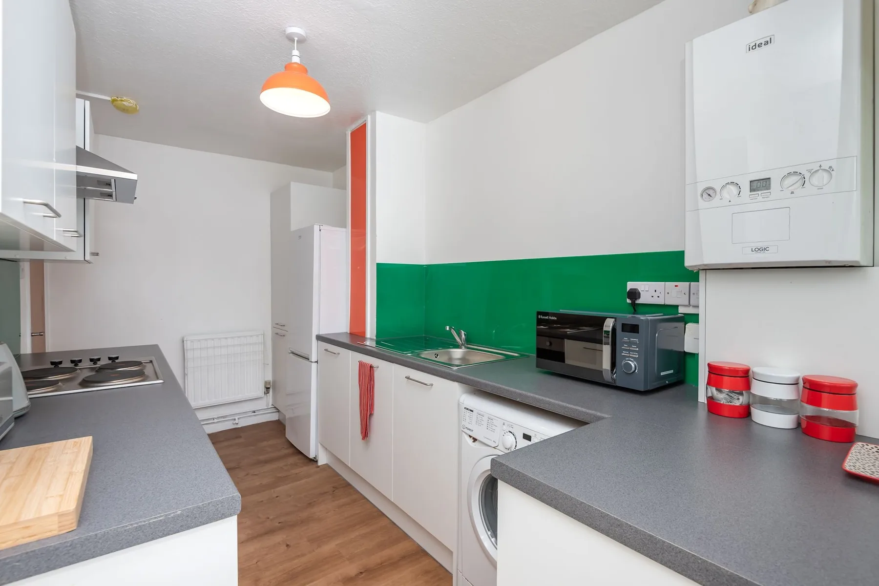 A bright kitchen with a green backsplash and countertop appliances.