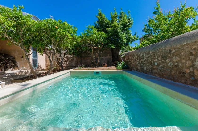 A swimming pool sits in a walled garden surrounded by trees.