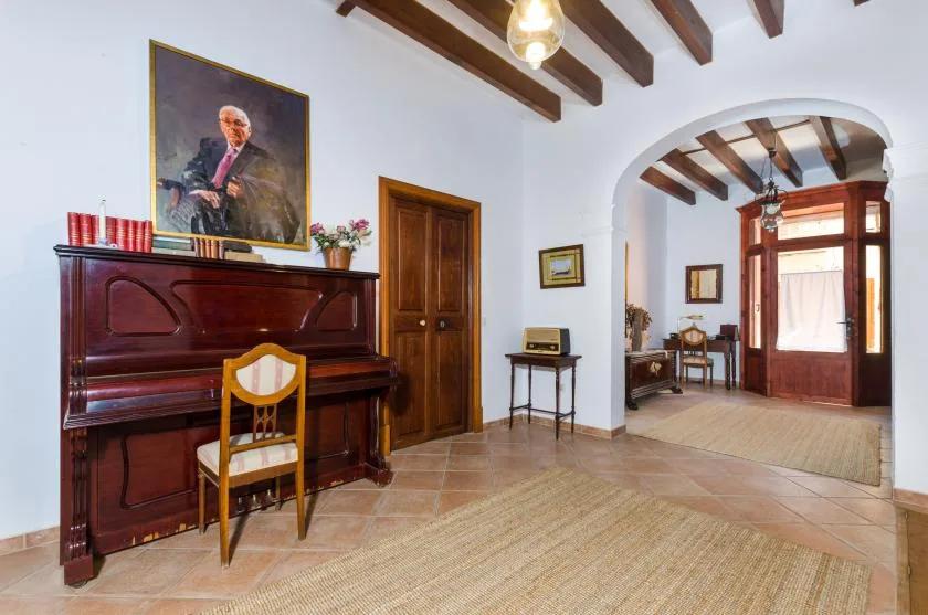 A piano sits against the wall in a room with exposed wooden ceiling beams.