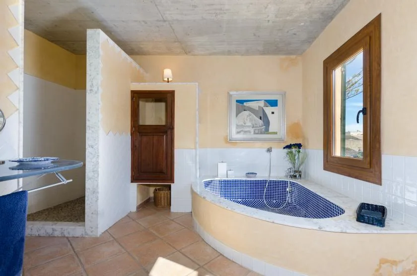 A tiled bathroom with a curved bathtub and a window.