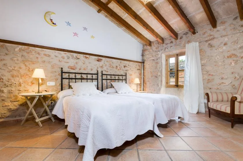 A bedroom with two beds, white bedding, and exposed ceiling beams.
