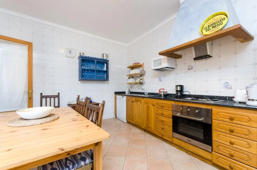 A kitchen with wooden cabinets, a countertop, and a dining table.