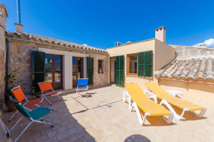 A sunny terrace with lounge chairs and shuttered doors.