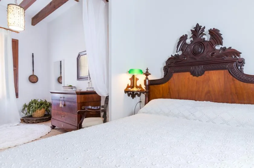 A bedroom with a carved wooden bed and a writing desk.