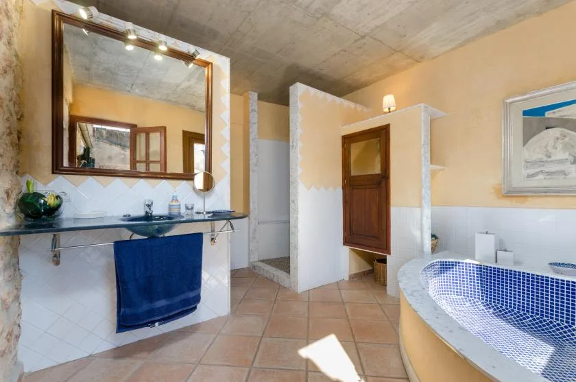 A bathroom with a sink, mirror, and blue-tiled bathtub.