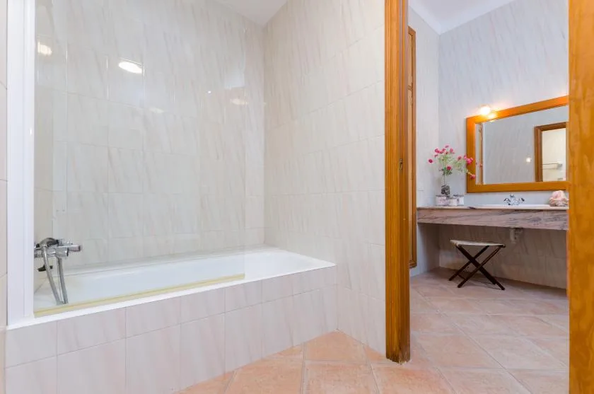 A tiled bathroom with a bathtub and a vanity area beside it.