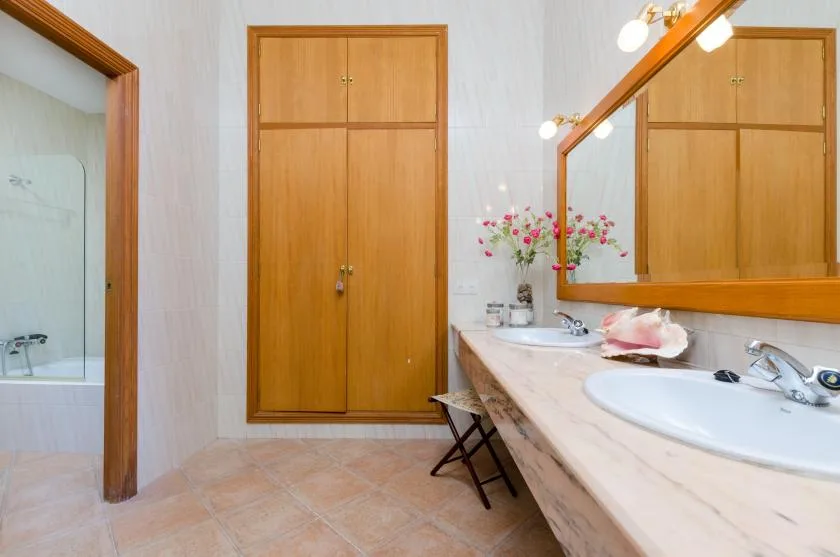 A bathroom with a long vanity, sink, and large wall mirror.