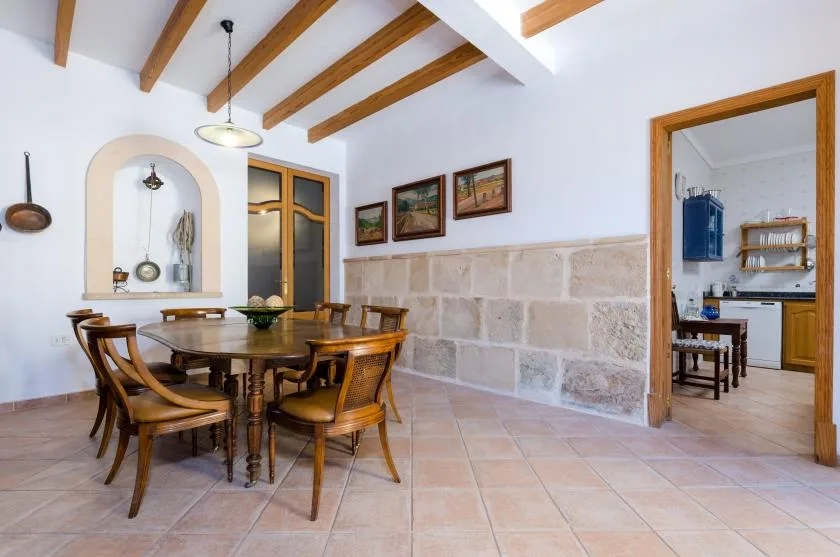 A dining area with a wooden table and chairs beneath exposed ceiling beams.