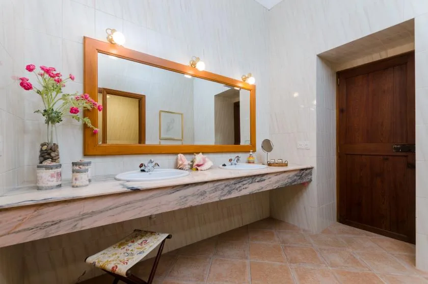 A bathroom vanity with a long counter, sink, and large wall mirror.
