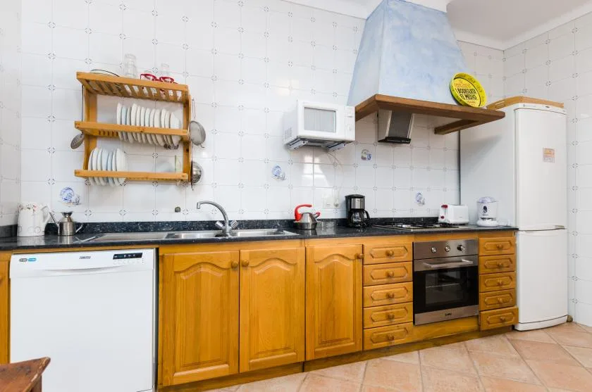 A tiled kitchen with wooden cabinets, a countertop, and built-in appliances.