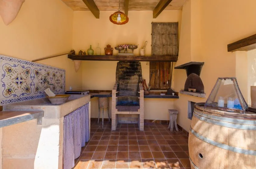 A rustic kitchen with a tiled counter and a large wooden barrel.