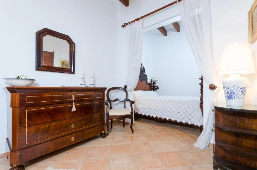A bedroom with a bed beneath a white canopy and wooden furnishings.