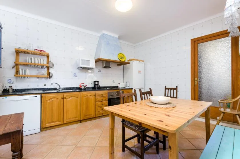A kitchen with wooden cabinets and a dining table in the center.