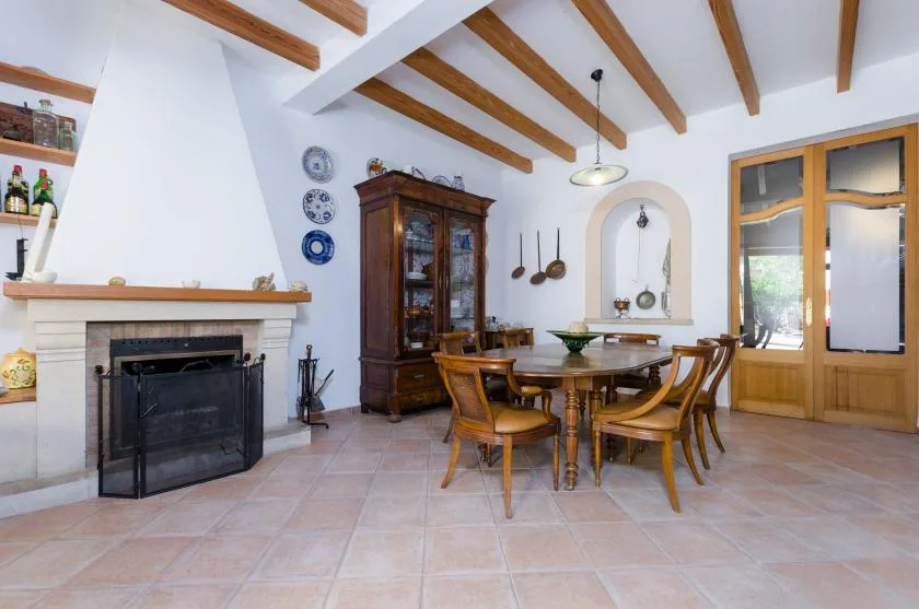 A dining area with a wooden table and chairs beside a fireplace.