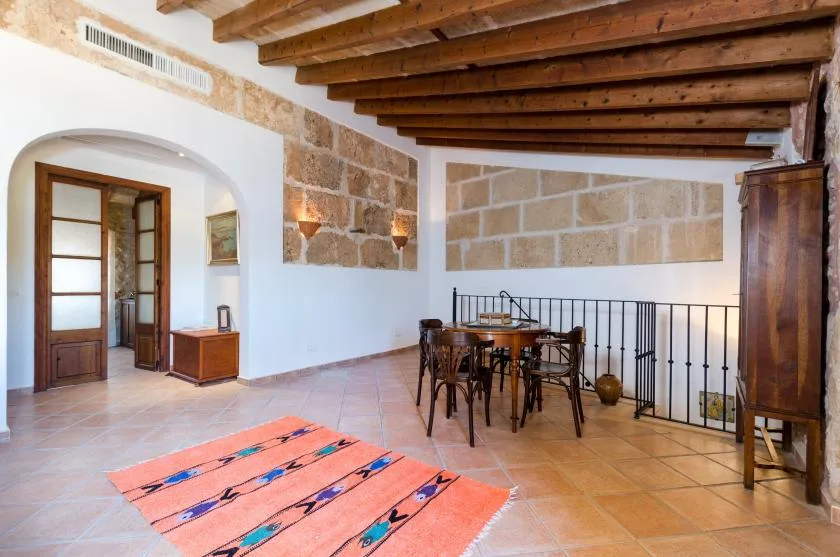 A dining area with a wooden table and chairs beneath exposed ceiling beams.