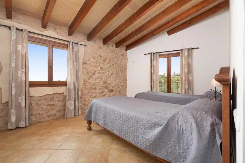 Un dormitorio con dos camas, vigas de madera expuestas y paredes de piedra.