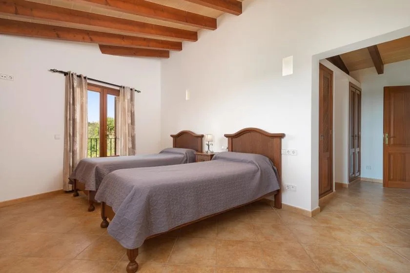 Un dormitorio con dos camas, vigas de madera a la vista y una puerta acristalada.