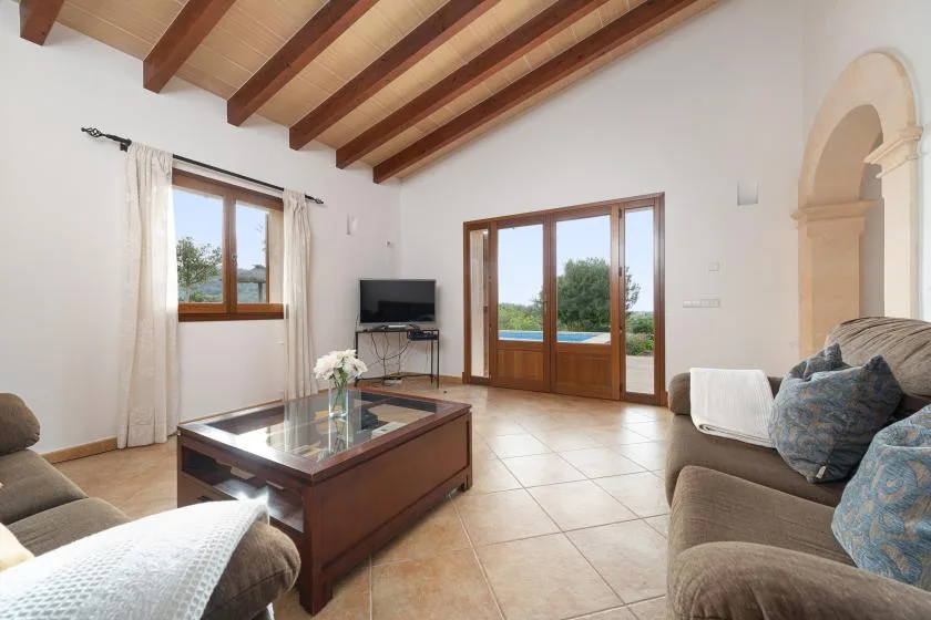 Una sala luminosa con asientos, una mesa de centro y puertas acristaladas con marco de madera.