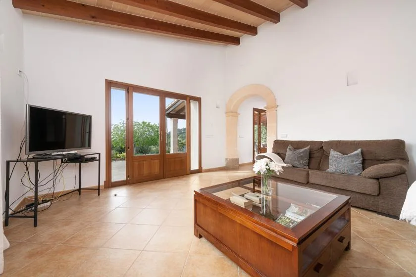Una sala de estar con un televisor, asientos y una mesa de centro de madera.