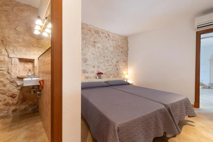 Un dormitorio con dos camas junto a una pared de piedra vista.