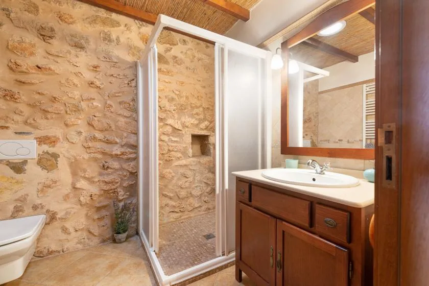 Un baño rústico con ducha y un mueble de lavabo de madera.