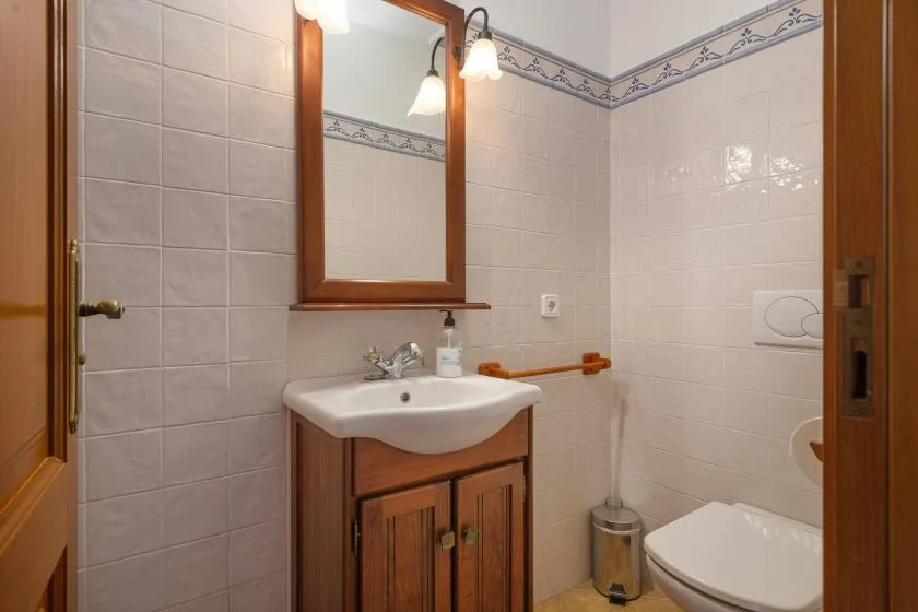 Un baño alicatado con lavabo, espejo e inodoro.